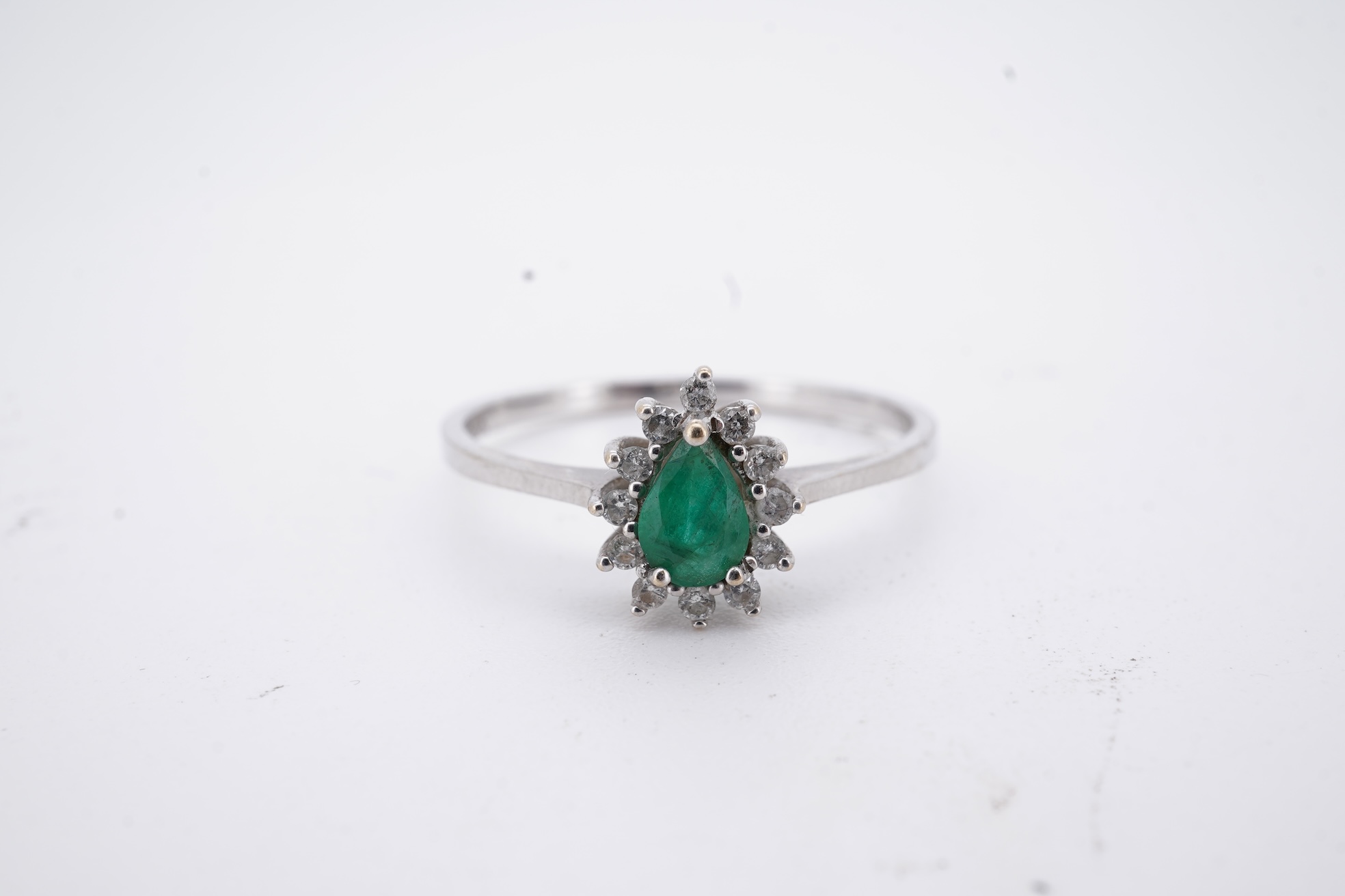 A modern white metal(stamped 14k), emerald and diamond set pear shaped cluster ring, size R, gross weight 1.3 grams.